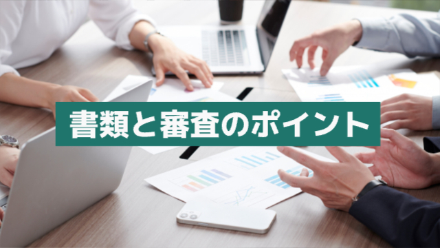 書類やパソコンを持って集まった人たちが話し合っている様子(手元のみ写っている)「書類と審査のポイント」
