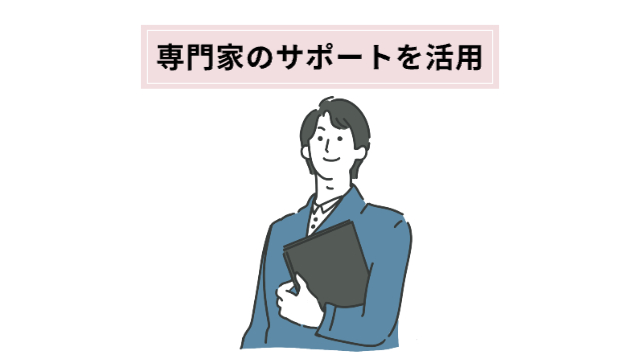 行政書士らしき男性が書類を持ってこっちを向いて微笑んでいる「専門家のサポートを活用」
