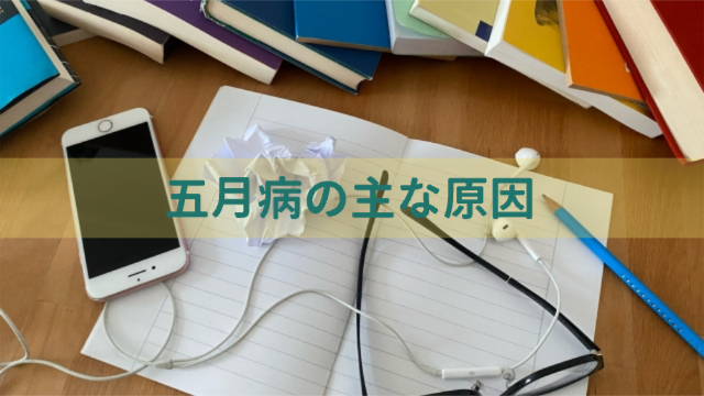 机の上にノートやぐちゃぐちゃの紙、イヤホンなどが置かれている「五月病の主な原因」
